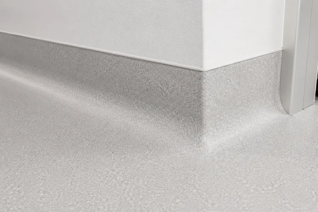 Close-up of sheet-vinyl flooring coved continuously up the wall as an integral base