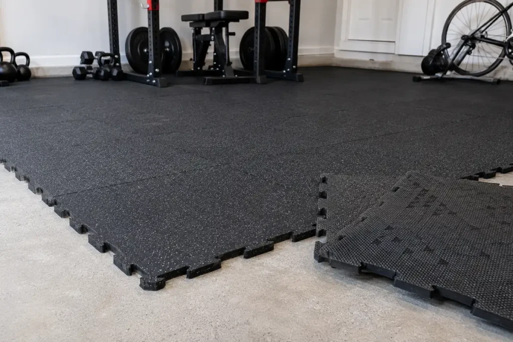 Interlocking rubber gym tiles with puzzle edges being laid in a home gym