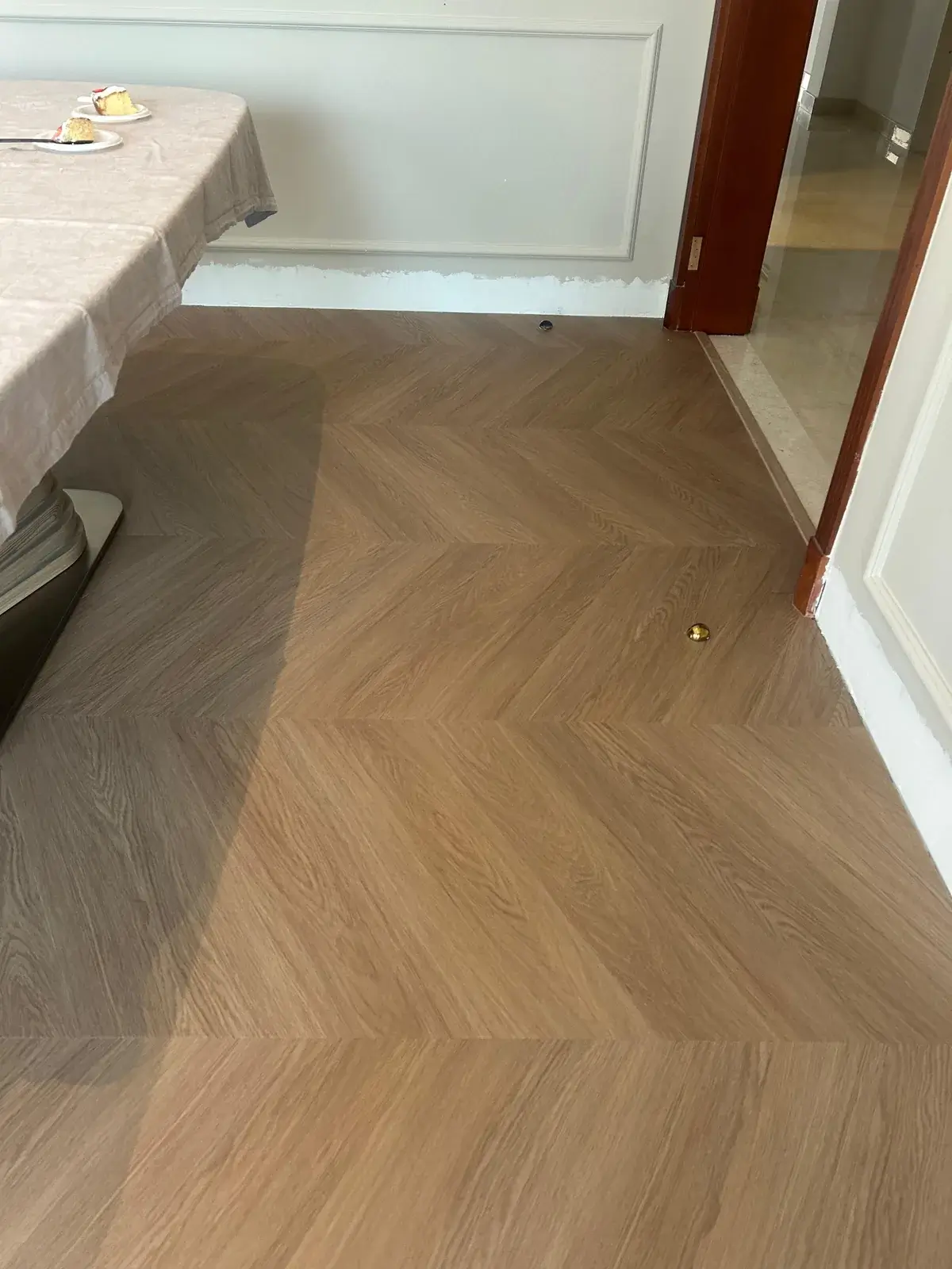 Chevron wood-look flooring meeting an existing tiled floor at a doorway threshold, Costa Brava Dubai