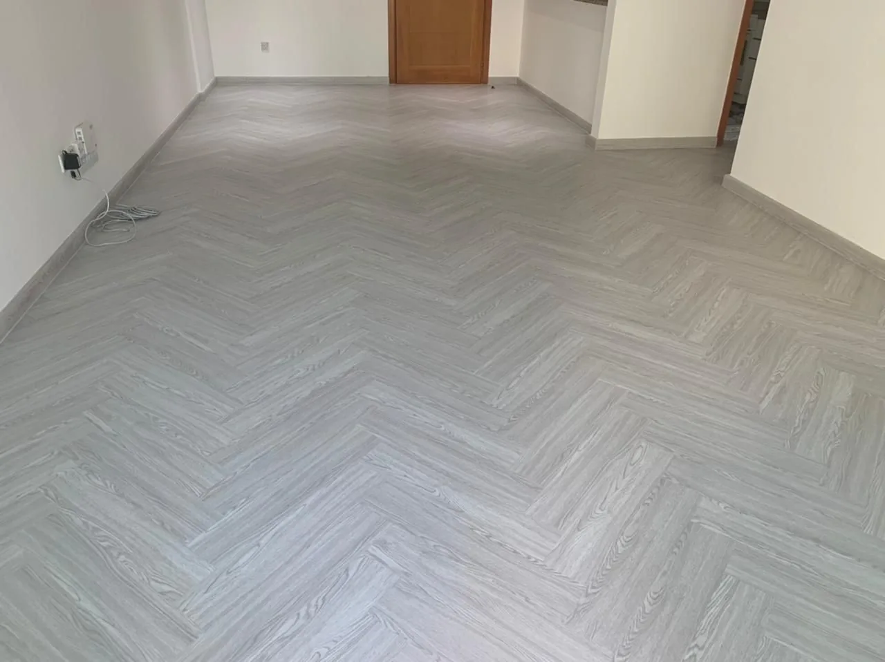 Grey oak herringbone SPC flooring in an Al Mamzar apartment living room, Dubai
