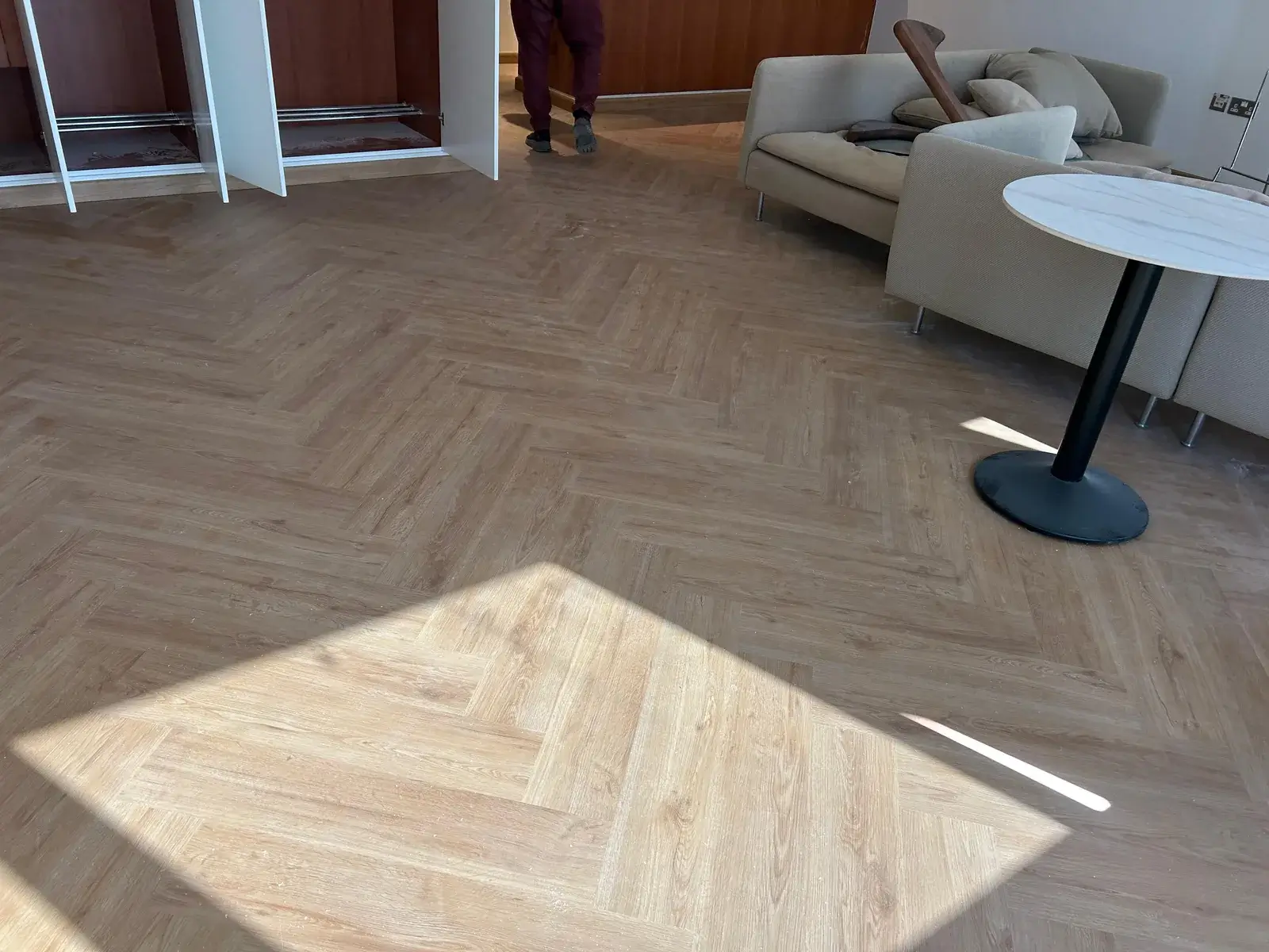 Warm natural-oak herringbone SPC flooring in a Valia Tower living room, Dubai Creek Harbour