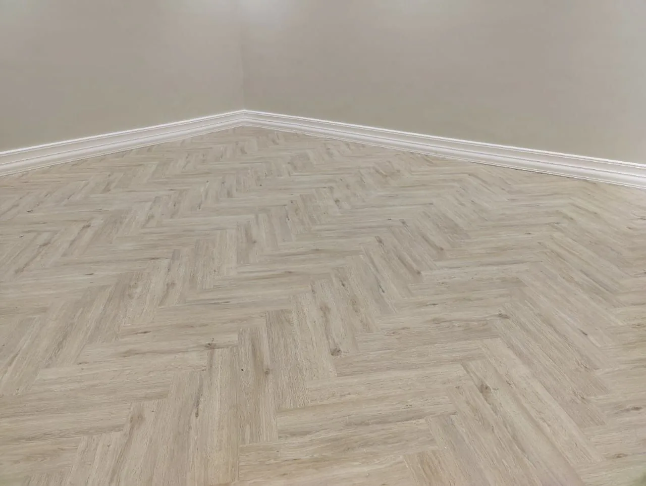 Light natural herringbone SPC flooring in an Al Mamzar apartment room, Dubai