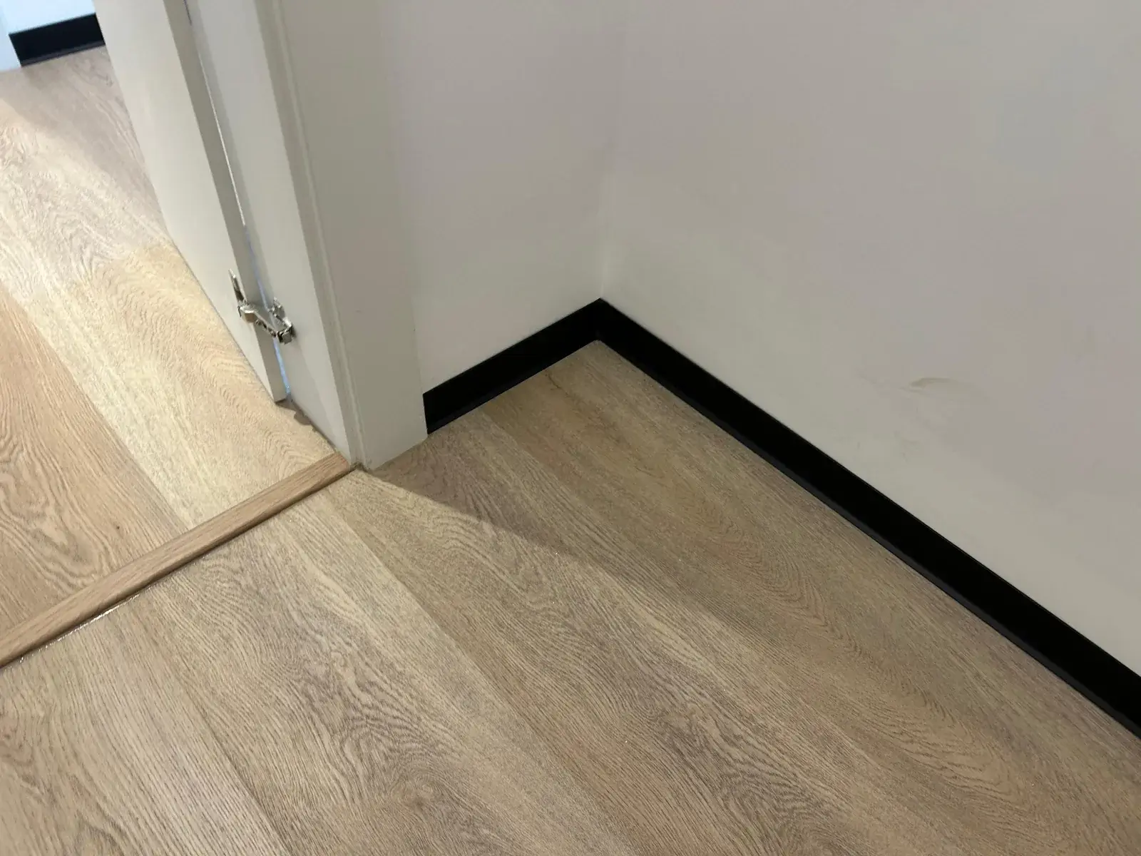 SPC flooring meeting a doorway threshold trim with black skirting, Al Nahda 2 Dubai