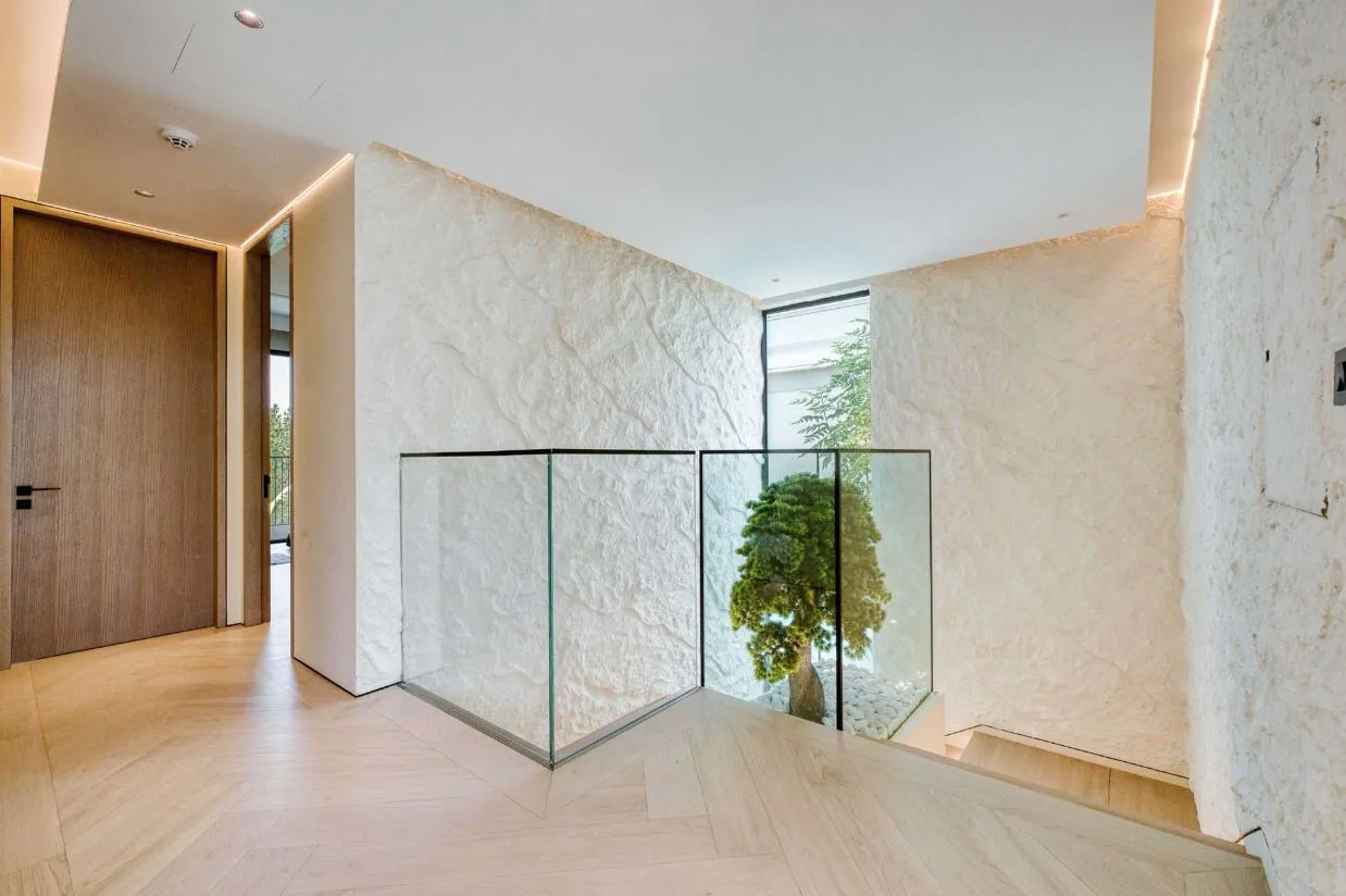 Wood-look SPC chevron flooring on a villa staircase landing with glass balustrade, Dubai