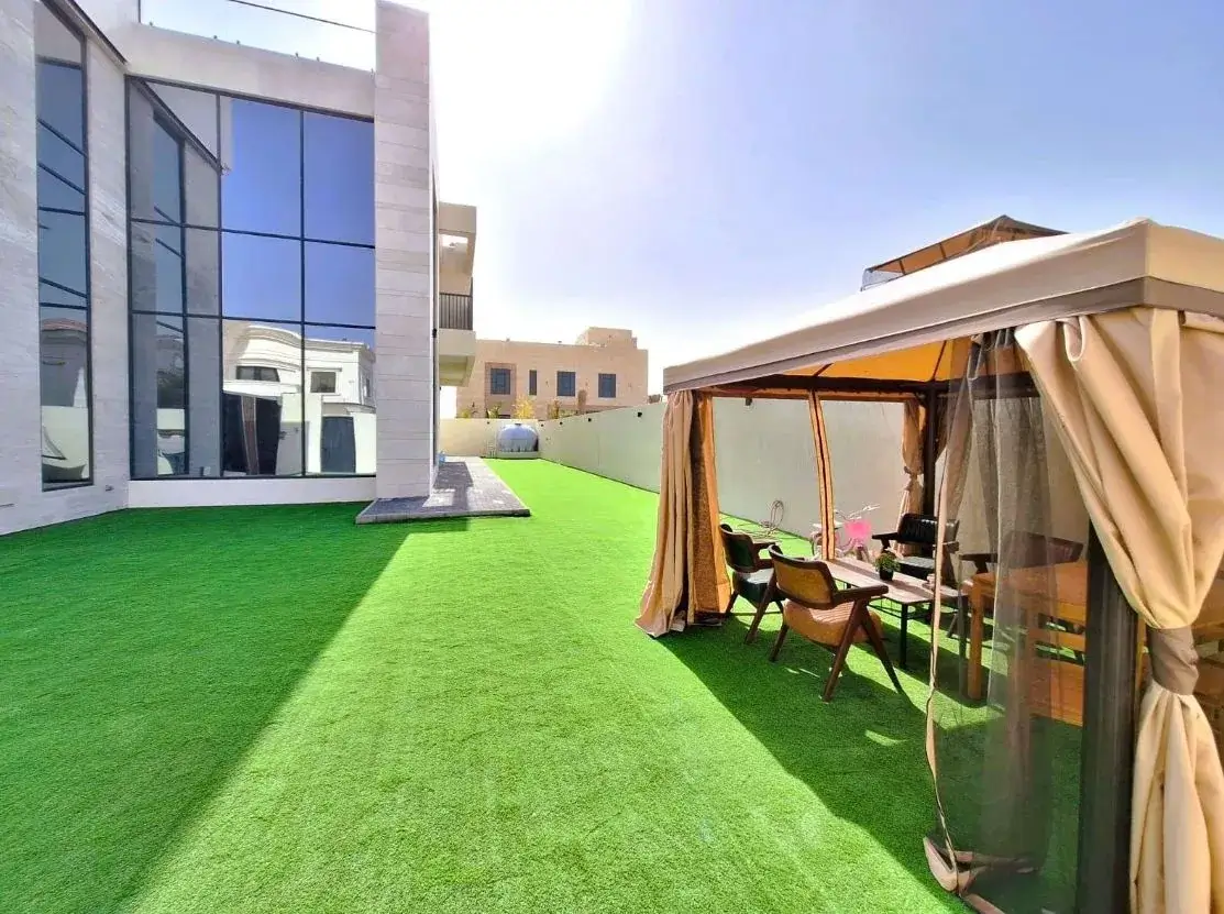 Artificial grass laid alongside a villa with a shaded seating area, Al Suyoh Sharjah