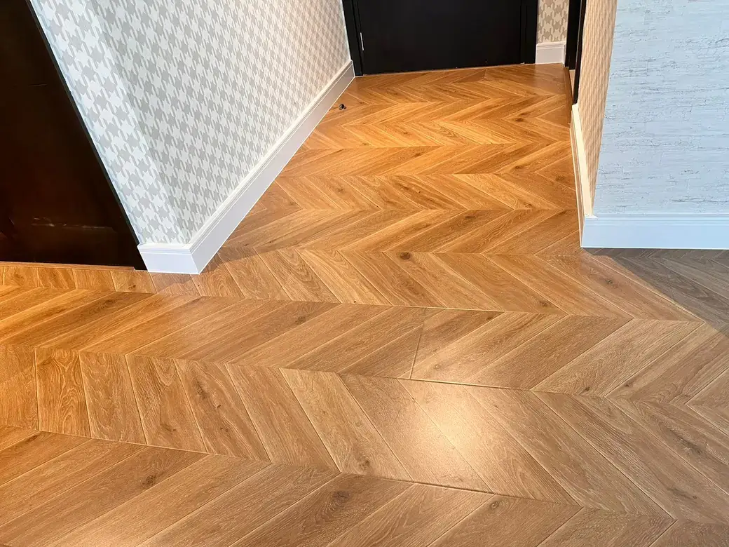Light oak chevron engineered wood flooring meeting a darker floor at a doorway threshold in a Cloud 9 apartment, Al Sufouh, Dubai