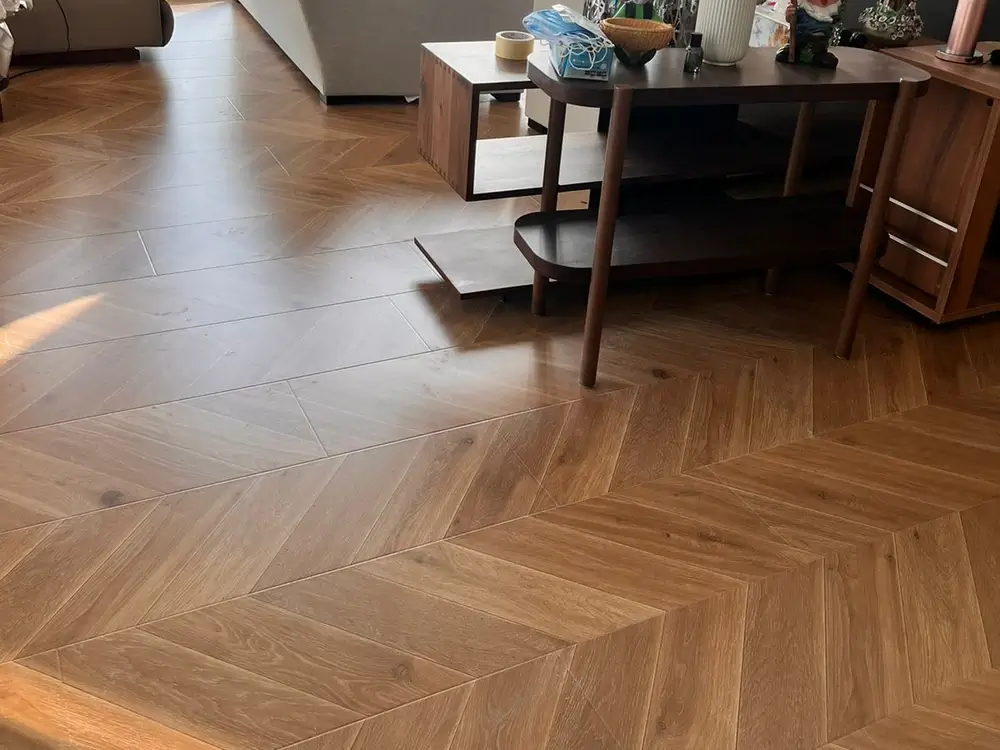 Chevron engineered wood flooring running through the living area of a Dubai apartment with floor-to-ceiling windows
