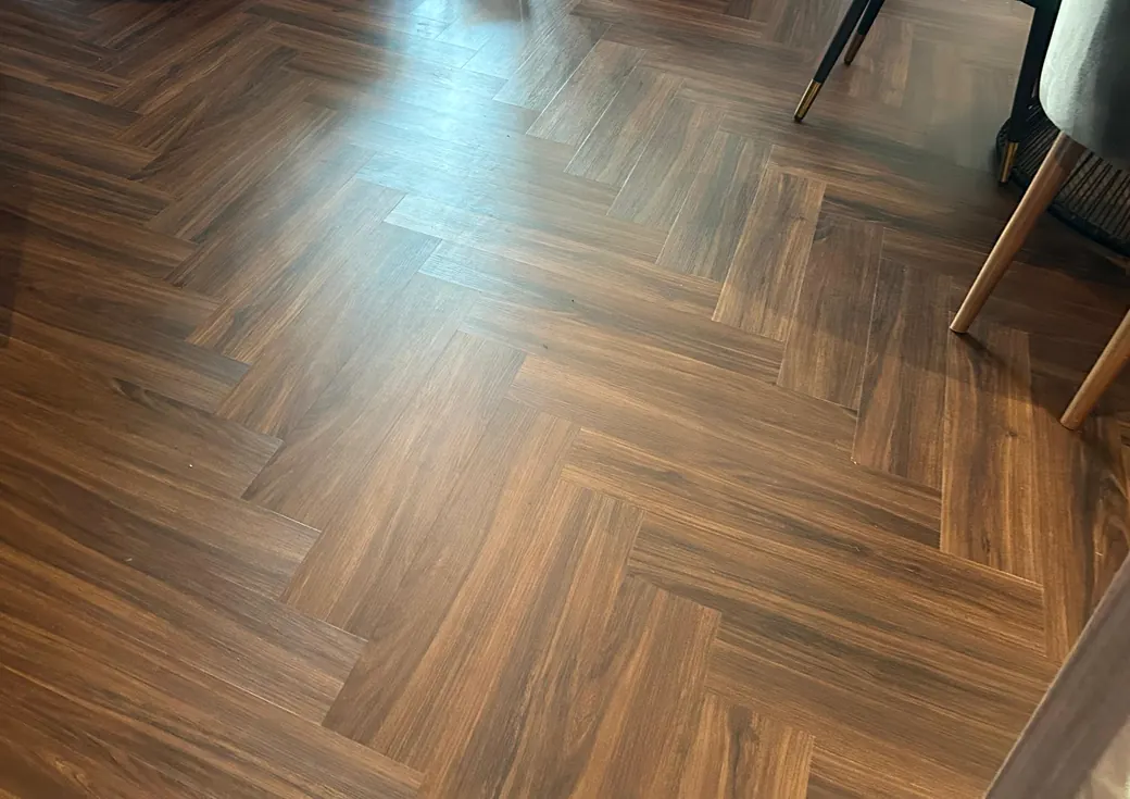 Herringbone LVT flooring in dark walnut across an apartment living area at Land Residence Complex, Dubai