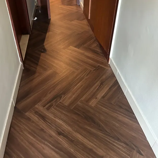 Herringbone LVT flooring running down an apartment corridor at Land Residence Complex, Dubai