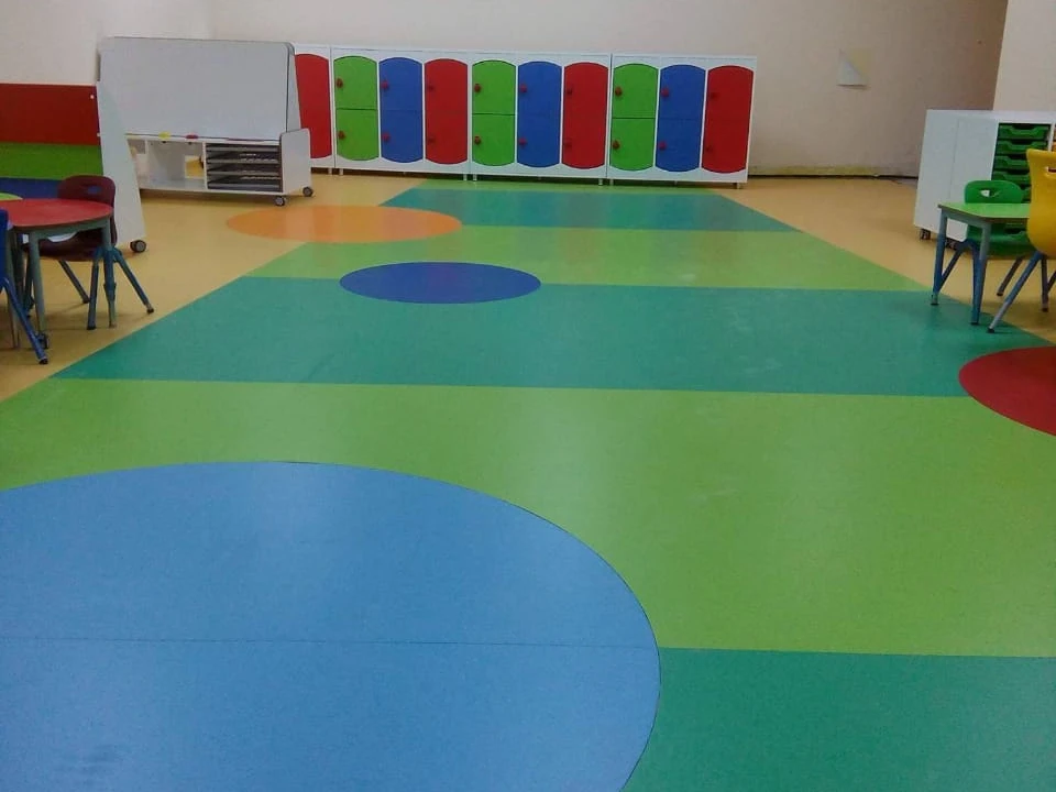 Green, teal and yellow sheet vinyl flooring with inlaid circles across a Dubai nursery classroom