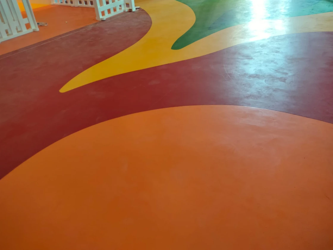 Welded sheet vinyl flooring in orange, red, yellow and green curved sections in a Dubai nursery play area
