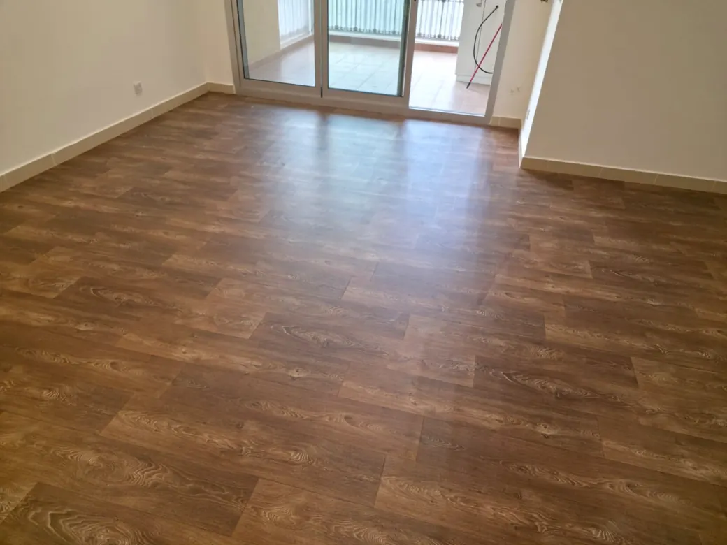 Wood-look sheet vinyl flooring across an open living area in a Y Tower apartment, Al Reem Island, Abu Dhabi