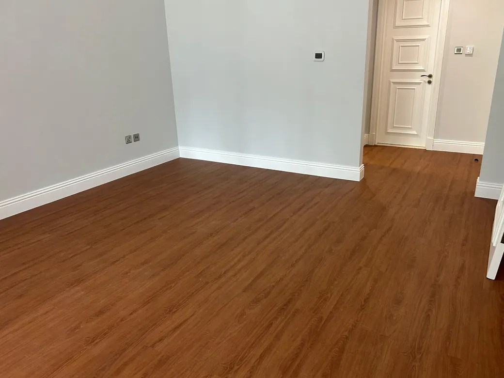 Warm oak WPC plank flooring in an empty bedroom running through to the corridor, Enaya Residences, JVT Dubai