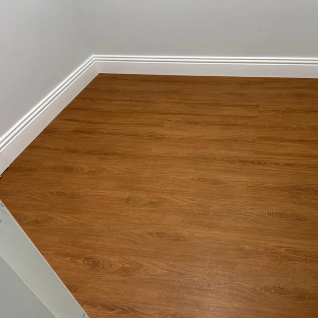 Warm oak WPC plank flooring in an empty room with white skirting, Enaya Residences JVT Dubai