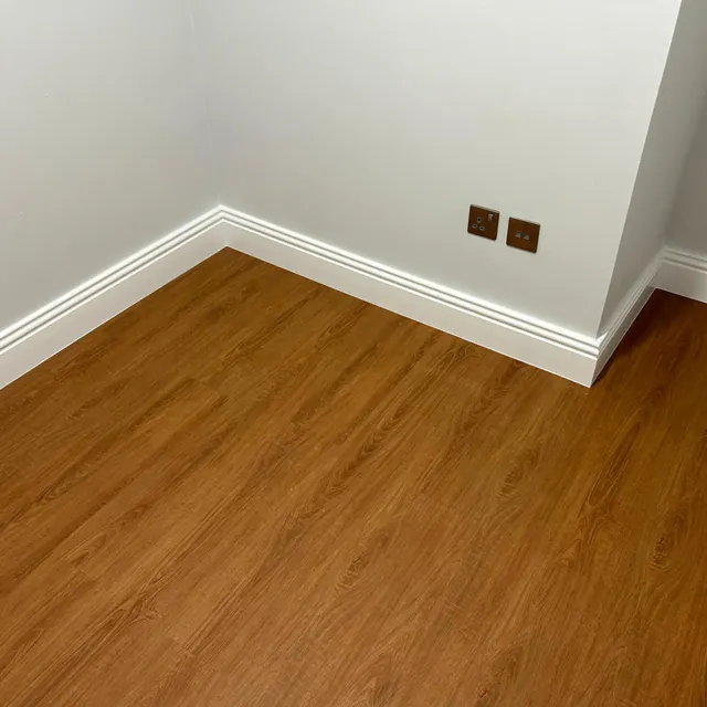 Close view of warm oak WPC plank flooring meeting white skirting in a corner, Enaya Residences JVT